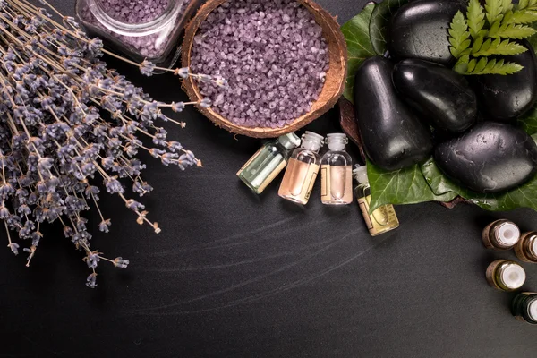 Spa konsept taşlar, çiçek, uçucu yağlar ve ahşap masa üzerinde mineral tuz 