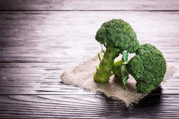 Bunch of fresh green broccoli on brown plate over wooden background — Stock Photo, Image