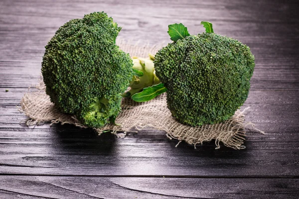 Bunch of fresh green broccoli on brown plate over wooden background — Stock Photo, Image