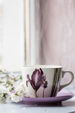 Pencere whith bahar çiçek yanında sıcak bir içecek Kupası