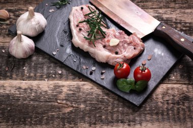 Taze kasap et ürün yelpazesine ahşap masa üzerinde taze biberiye ile süslenmiş kesmek