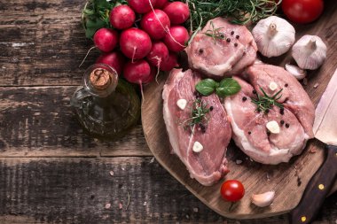 Taze kasap et ürün yelpazesine ahşap masa üzerinde taze biberiye ile süslenmiş kesmek