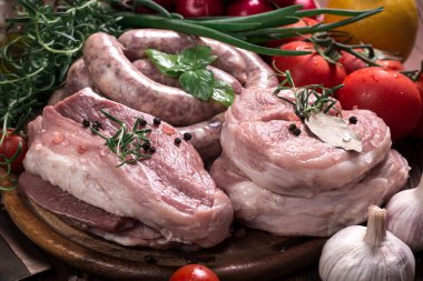 Taze kasap et ürün yelpazesine ahşap masa üzerinde taze biberiye ile süslenmiş kesmek