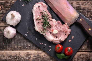 Taze kasap et ürün yelpazesine ahşap masa üzerinde taze biberiye ile süslenmiş kesmek