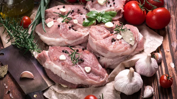 Carnicero fresco corte surtido de carne adornado con romero fresco en mesa de madera — Foto de Stock