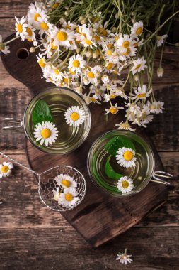 ahşap bir masa üzerinde bitkisel papatya çayı. Ahşap masa üzerinde şeffaf bir fincan ve papatya çiçek papatya çayı. Bebeğin mide bitki çayı. Kopya alanı.