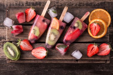 Ahşap antika masa üzerinde çilek Çilek kivi ile sağlıklı tüm meyve Popsicles