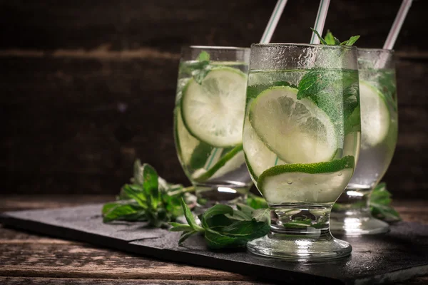 Detox water with a lemon, lime and mint on a wooden table — Stock Photo, Image