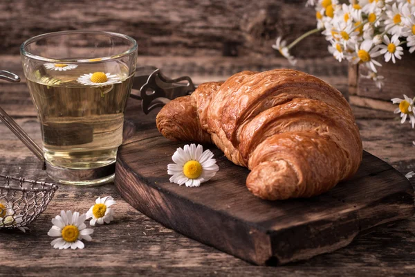 Frukost med örtte och croissant på vintage träbord — Stockfoto