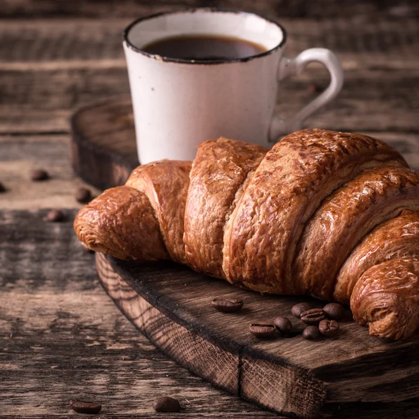 Frukost med kaffe och croissanter på vintage träbord — Stockfoto