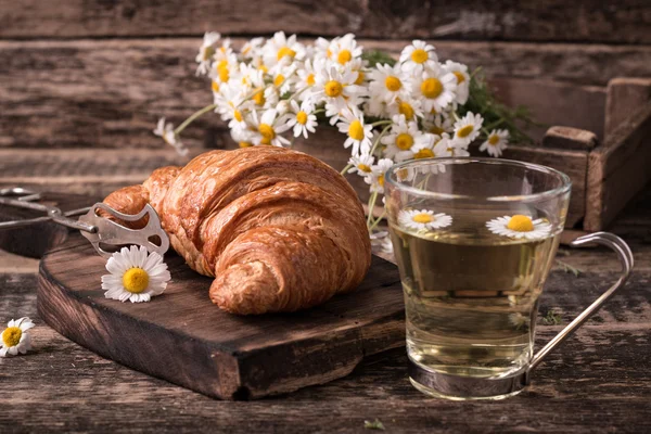 Frukost med örtte och croissant på vintage träbord — Stockfoto