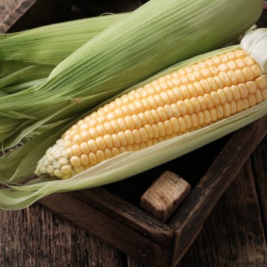 Kırsal ahşap masadaki koçanlarda taze mısır, yakın plan.
