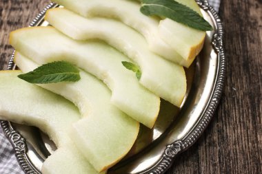 Dilimlenmiş taze kavun ve ahşap masa, sağlıklı gıda nane