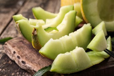 Dilimlenmiş taze kavun ve ahşap masa, sağlıklı gıda nane