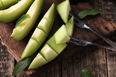 Dilimlenmiş taze kavun ve ahşap masa, sağlıklı gıda nane