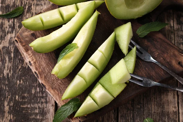 Dilimlenmiş taze kavun ve ahşap masa, sağlıklı gıda nane