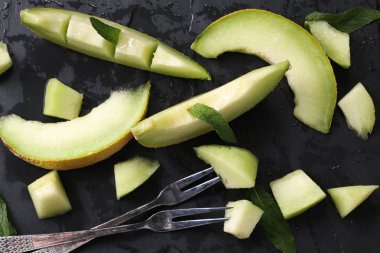 Dilimlenmiş taze kavun ve ahşap masa, sağlıklı gıda nane