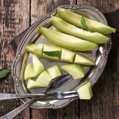 Dilimlenmiş taze kavun ve ahşap masa, sağlıklı gıda nane