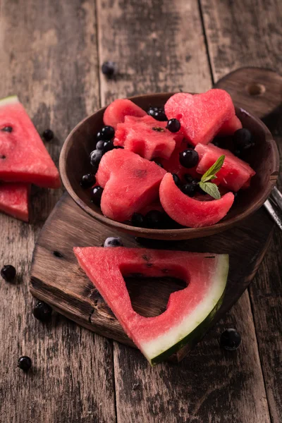Sommerlicher Obstsalat mit Wassermelone und Beeren. Scheiben von Wassermelone in Form eines Sterns, eines Herzens, eines Mondes. Holzhintergrund — Stockfoto