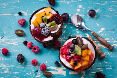 ahşap arka plan üzerinde iki Hindistan cevizi yaban mersini ve çilek servis.