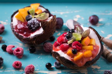 ahşap arka plan üzerinde iki Hindistan cevizi yaban mersini ve çilek servis.