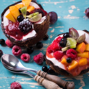 ahşap arka plan üzerinde iki Hindistan cevizi yaban mersini ve çilek servis.