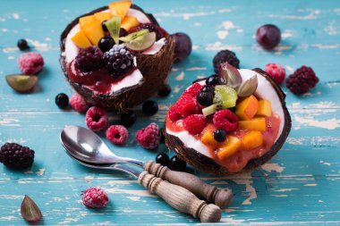 ahşap arka plan üzerinde iki Hindistan cevizi yaban mersini ve çilek servis.