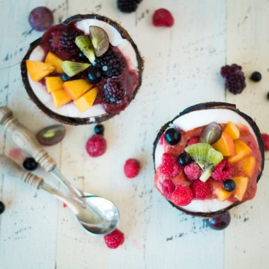 ahşap arka plan üzerinde iki Hindistan cevizi yaban mersini ve çilek servis.