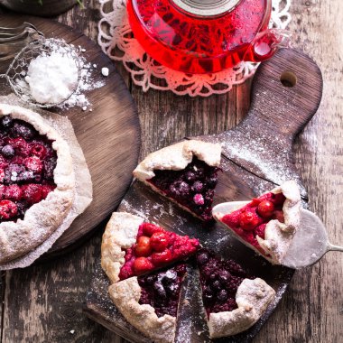 Yaban mersini, kiraz, ahududu ve blackcurrant Galette'ye w ahşap zemin üzerine.