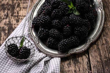 Ahşap arka plan üzerinde çuval bezi kumaş üzerine seramik bir kasede olgun böğürtlen kapatın. Rustik tarzı, seçici odak