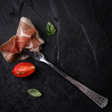 Fesleğenli domates ahşap kesme tahtası, antika arka plan üzerinde ince dilim jambon ile karışık