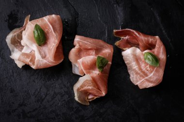 Fesleğenli domates ahşap kesme tahtası, antika arka plan üzerinde ince dilim jambon ile karışık