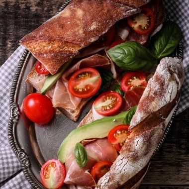 Ciabatta sandviç salam, avokado, kiraz domates ve fesleğen koyu arka plan üzerinde