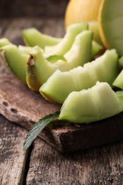 Dilimlenmiş taze kavun ve ahşap masa, sağlıklı gıda nane