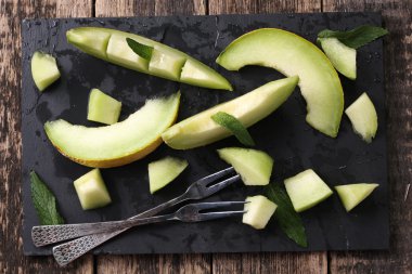 Dilimlenmiş taze kavun ve ahşap masa, sağlıklı gıda nane