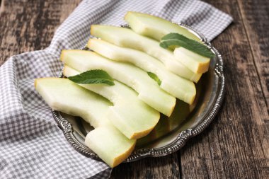 Dilimlenmiş taze kavun ve ahşap masa, sağlıklı gıda nane