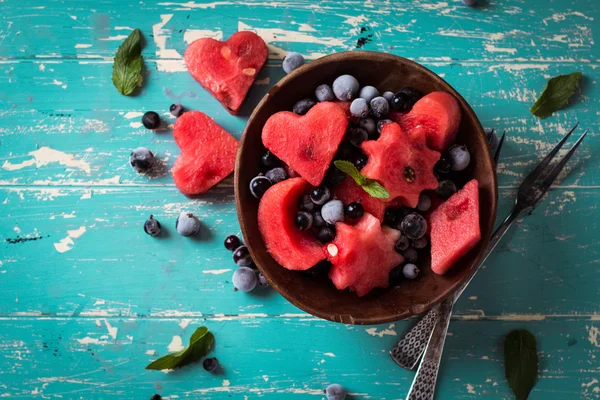 Insalata di frutta estiva di anguria e bacche. Fette di anguria a forma di stella, cuore, luna. Fondo in legno — Foto Stock