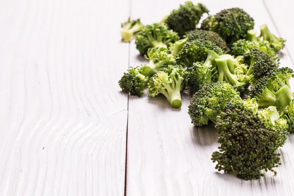 Bunch of fresh green broccoli on brown plate over wooden background — Stock Photo, Image