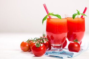 Beyaz ahşap zemin üzerinde taze domates ve domates suyu