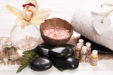Spa konsept taşlar, çiçek, uçucu yağlar ve ahşap masa üzerinde mineral tuz 
