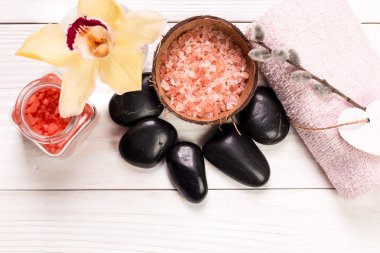 Spa konsept taşlar, çiçek, uçucu yağlar ve ahşap masa üzerinde mineral tuz 