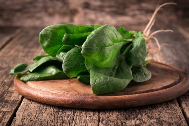 Bir avuç taze ıspanak kökleri eski ahşap yüzey üzerinde. Karanlık rustik tarzı