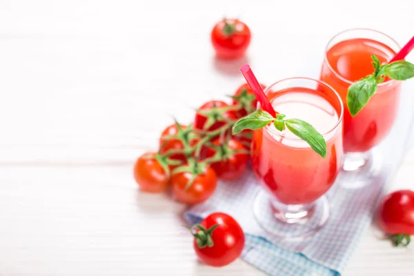 Jugo de tomate y tomates frescos en un fondo de madera blanca — Foto de Stock