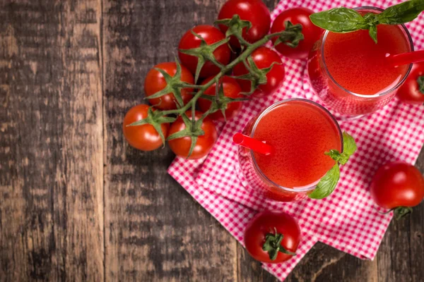 Tomatensap en verse tomaten op een houten achtergrond — Stockfoto