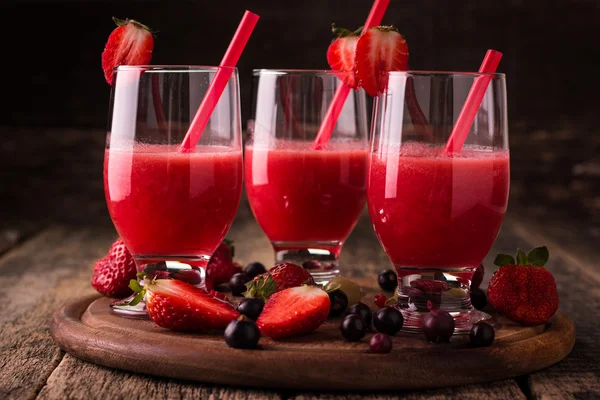 Стаканы свежего холодного смузи с фруктами и ягодами, на деревянном фоне, здоровый детоксикационный напиток — стоковое фото