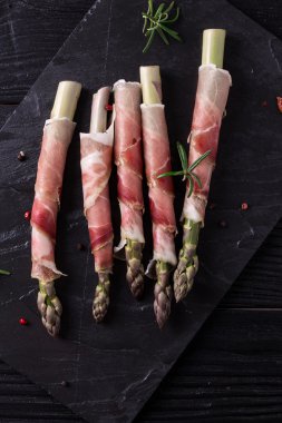 Parma jambonu bir kesme tahtası üzerinde sarılı taze organik kuşkonmaz 