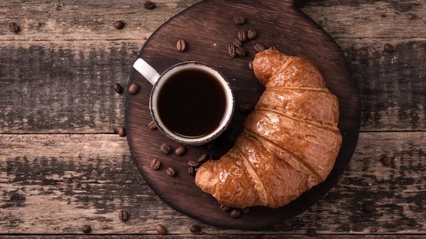 Frukost med kaffe och croissanter på vintage träbord — Stockfoto