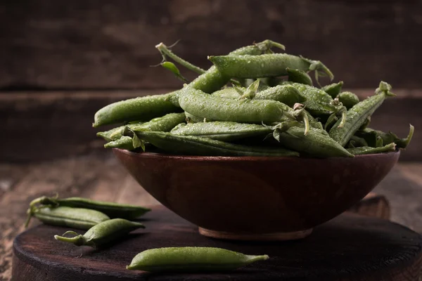 Pods of green peas on a wooden table, rustic style,healthy food — Stock Photo, Image