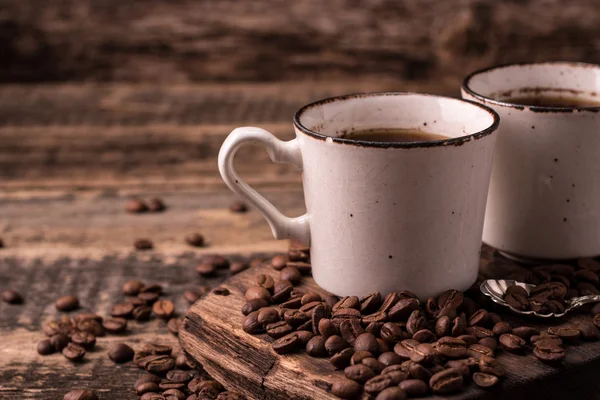 Kaffeetasse mit gerösteten Bohnen auf Holzgrund — Stockfoto