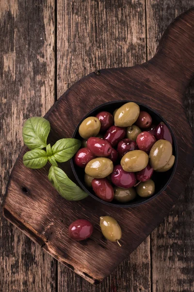 Aceitunas sobre mesa oscura de madera con albahaca —  Fotos de Stock